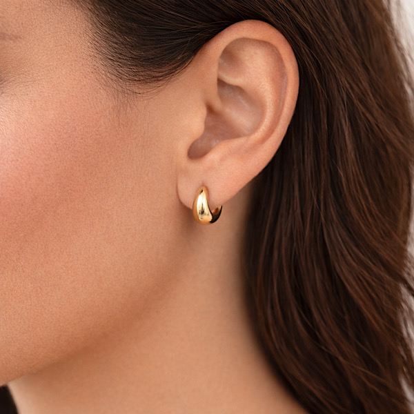 woman wearing gold huggie hoop earrings